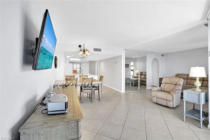 Living area featuring light tile patterned flooring, baseboards, visible vents, and arched walkways