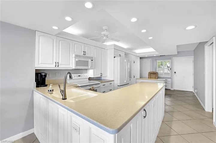 Kitchen featuring white appliances, recessed lighting, ceiling fan, and a sink