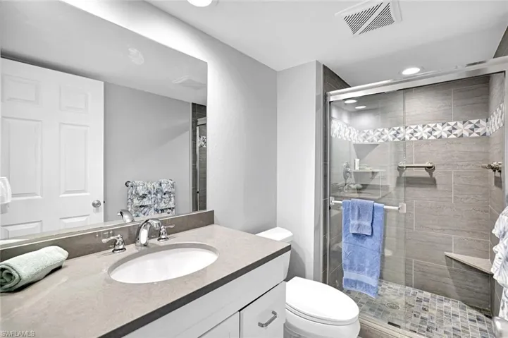 Full bath with vanity, recessed lighting, toilet, a shower stall, and visible vents