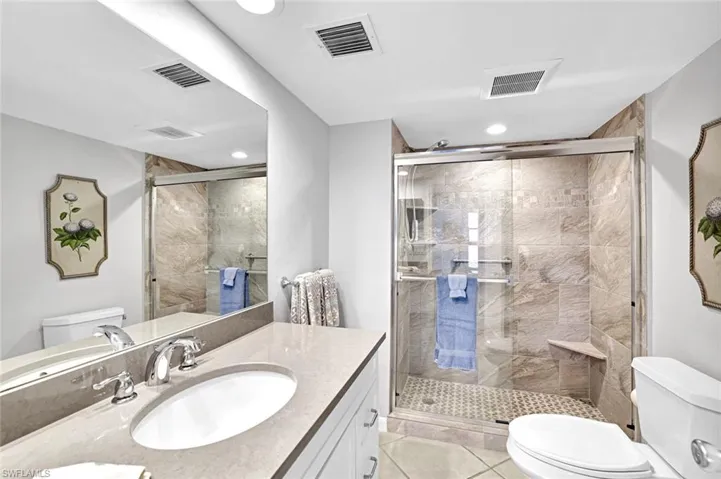 Bathroom with a shower stall, visible vents, and toilet
