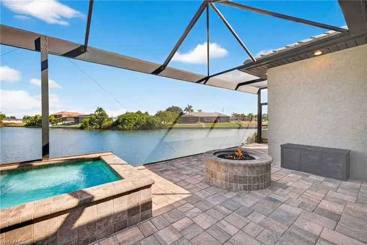 View of pool with a pool, a patio, an outdoor fire pit, and screen enclosure
