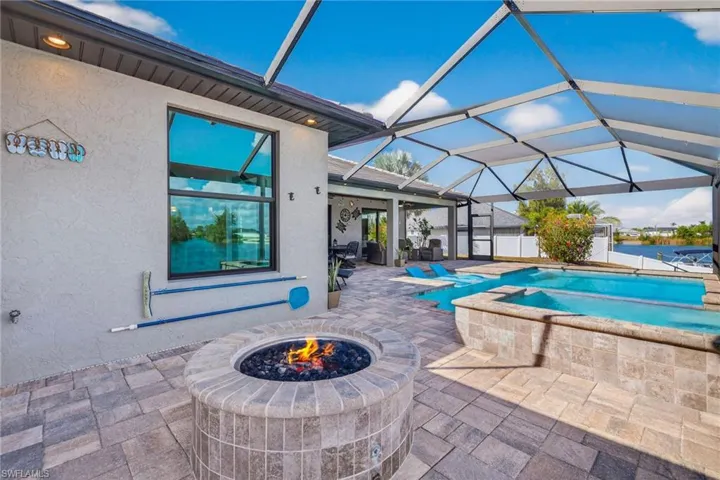 Swimming pool featuring a patio, a sunroom, a lanai, an in-ground hot tub, and a fire pit