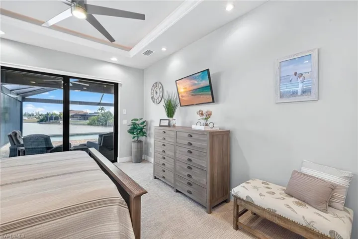 Carpeted bedroom featuring a water view, access to exterior, ornamental molding, a ceiling fan, and recessed lighting