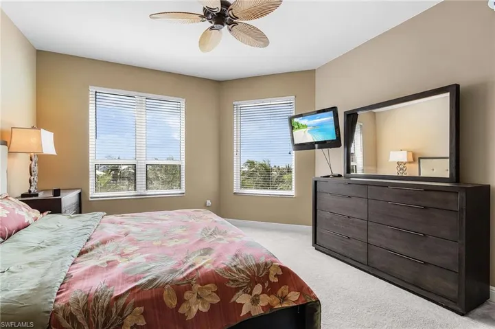 Bedroom with multiple windows, light colored carpet, and a ceiling fan