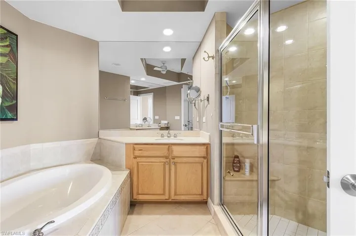 Bathroom with a stall shower, a bath, vanity, light tile patterned floors, and recessed lighting
