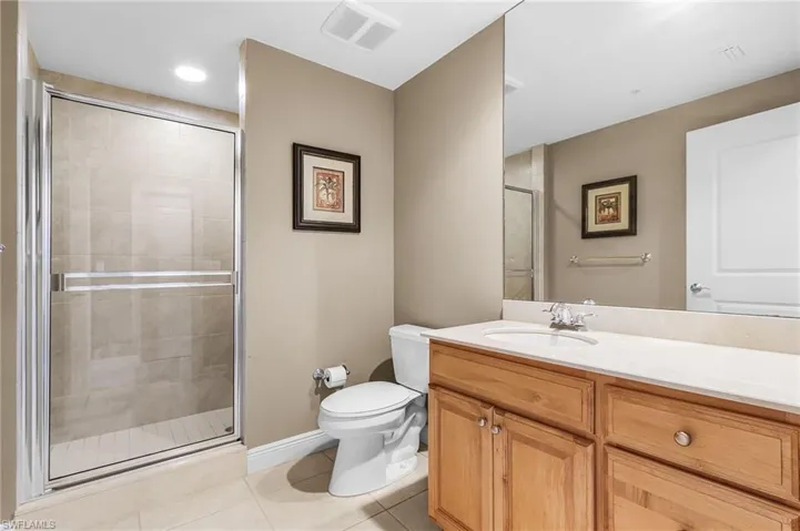 Bathroom with light tile patterned floors, a shower stall, and vanity
