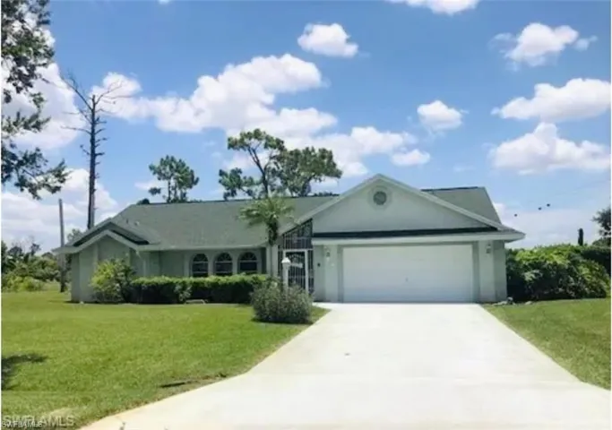 Single story home featuring a front yard, a garage, concrete driveway, and stucco siding