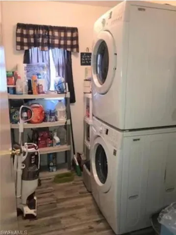 Laundry room with estacked washer and dryer and light wood-style flooring