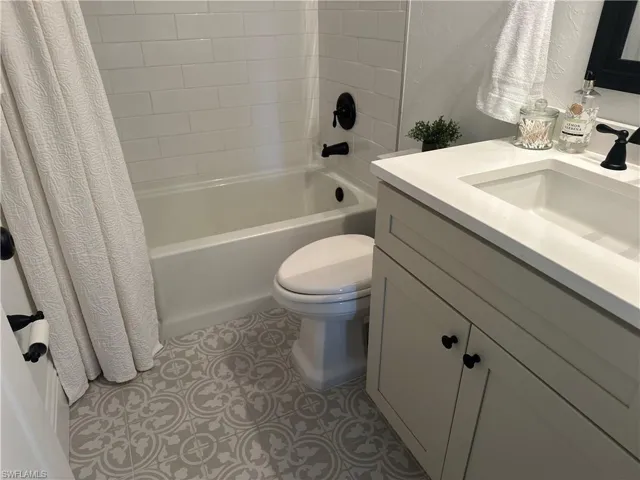 Full bathroom featuring vanity, toilet, and shower / bathtub combination with curtain
