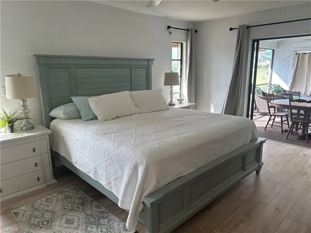 Bedroom with access to exterior, light wood-type flooring, and multiple windows