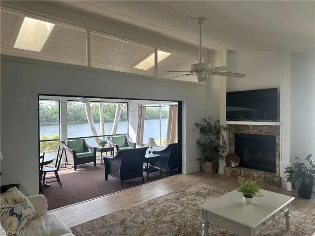 Living room featuring ceiling fan, a water view, a healthy amount of sunlight, and hardwood / wood-style flooring