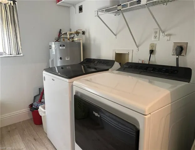 Separate Laundry room with electric water heater, washer and clothes dryer, and light hardwood / wood-style floors