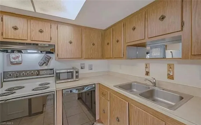 Kitchen with dishwasher, sink, white electric stove, and light tile floors