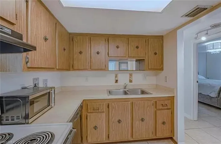 Kitchen with sink, range, and light tile floors