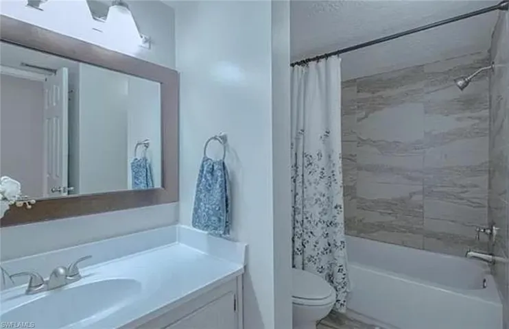 Full bathroom with shower / bath combo, toilet, and large vanity