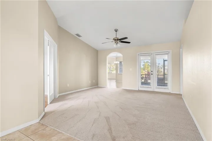 Carpeted empty room featuring ceiling fan and vaulted ceiling
