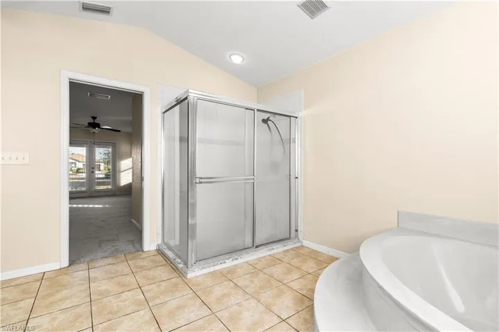 Bathroom featuring tile patterned flooring, ceiling fan, plus walk in shower, and vaulted ceiling