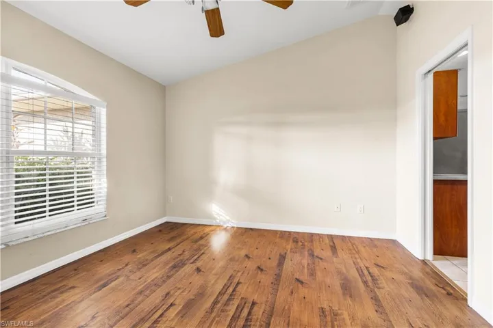 Unfurnished room with lofted ceiling, ceiling fan, and wood-type flooring