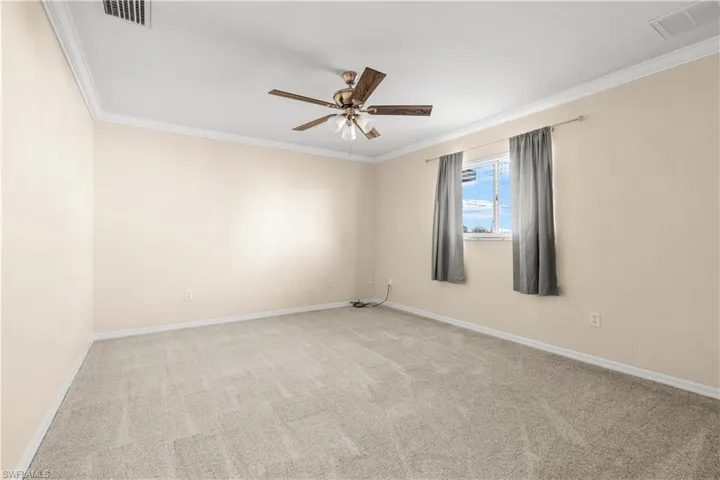 Unfurnished room featuring light carpet, ceiling fan, and ornamental molding