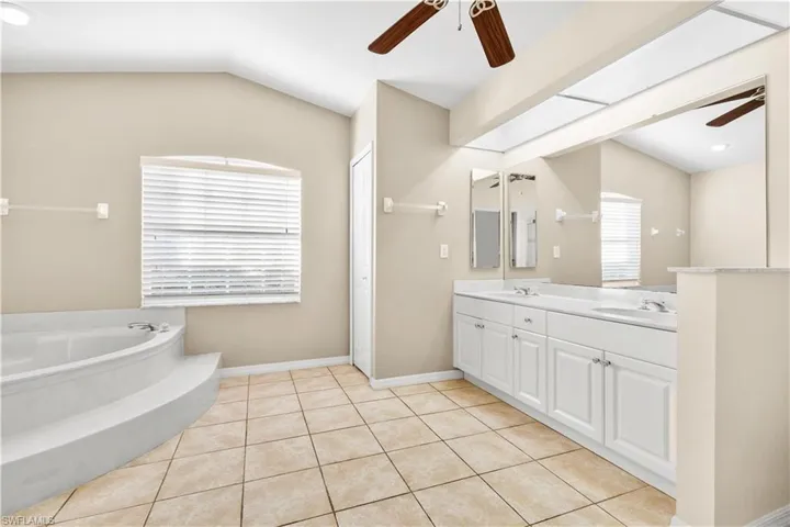 Bathroom with tile patterned floors, vanity, a bathing tub, and lofted ceiling