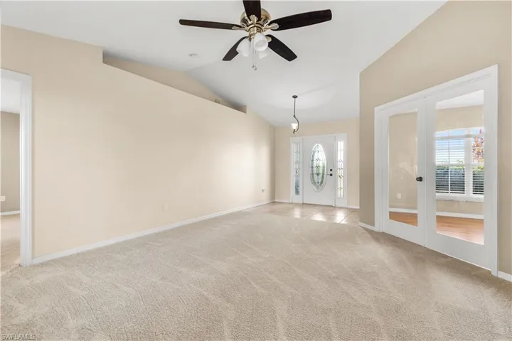 Empty room with light carpet, french doors, ceiling fan, and lofted ceiling