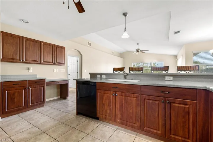 Kitchen with a wealth of natural light, pendant lighting, lofted ceiling, and black dishwasher