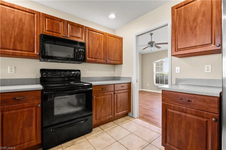 Kitchen with ceiling fan, light tile patterned flooring, and black appliances