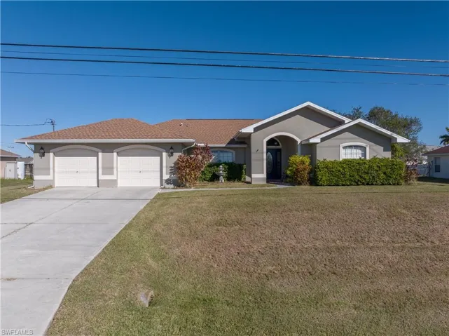 Ranch-style house with a garage and a front lawn