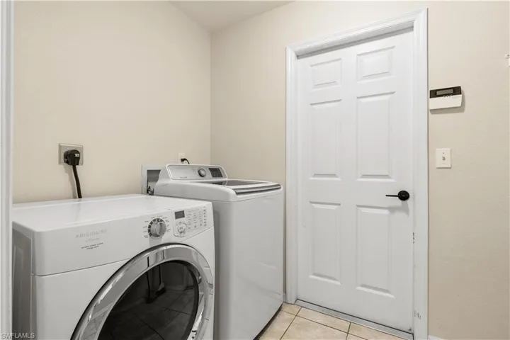 Laundry area with washer and clothes dryer and light tile patterned floors
