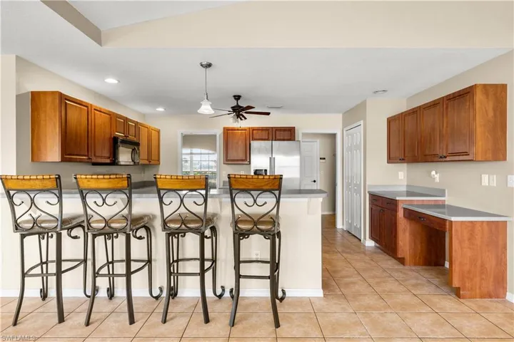 Kitchen with a kitchen bar, high end refrigerator, ceiling fan, light tile patterned floors, and lofted ceiling