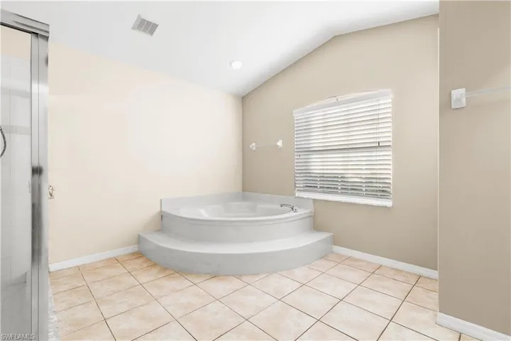 Bathroom with tile patterned floors, lofted ceiling, and a tub