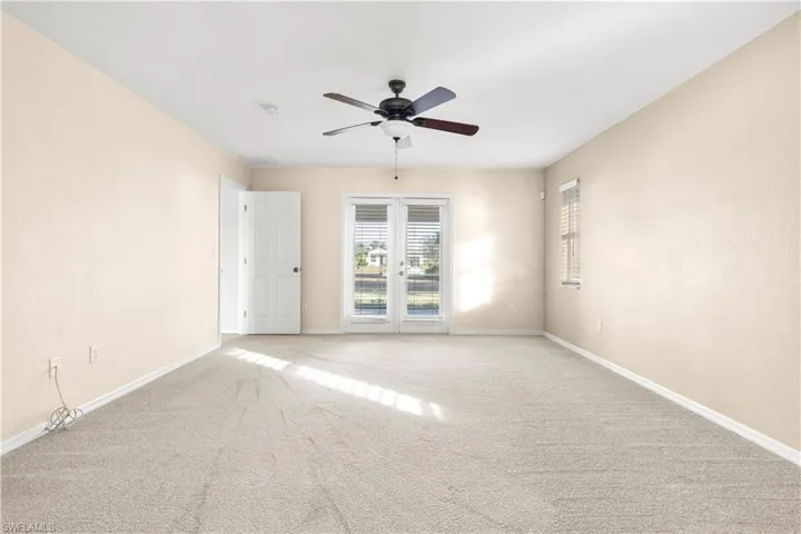 Empty room featuring ceiling fan, french doors, and carpet floors