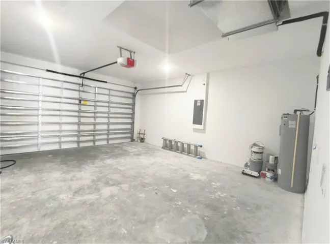 Garage featuring a garage door opener, water heater, and electric panel