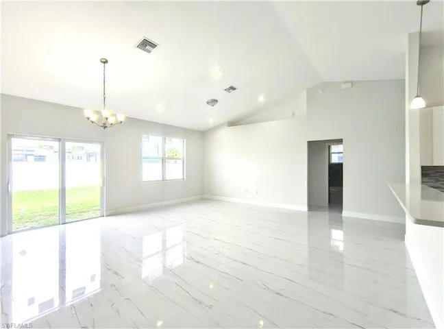Empty room featuring an inviting chandelier and high vaulted ceiling