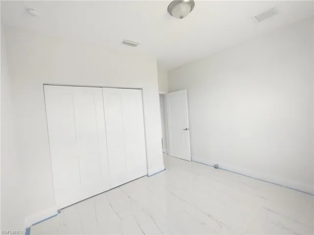 Unfurnished bedroom with a closet and light tile flooring