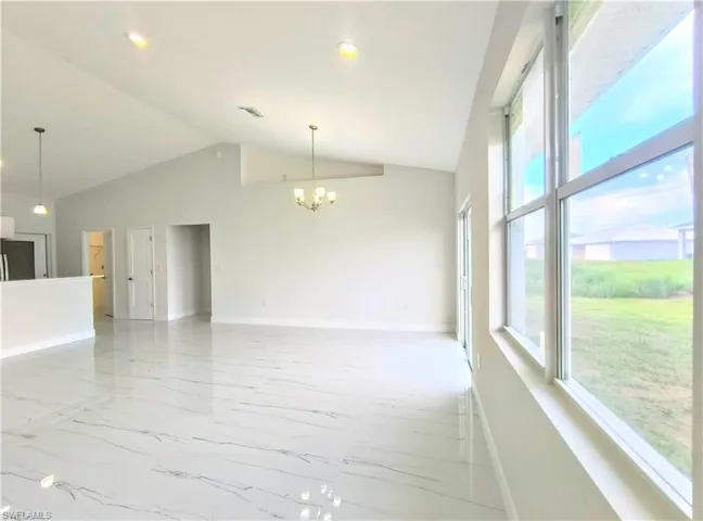 Unfurnished living room with an inviting chandelier, a wealth of natural light, and light tile patterned floors