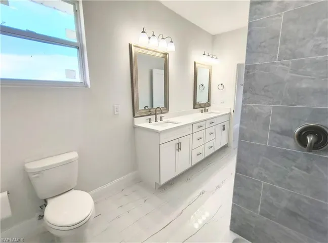 Bathroom with tile patterned flooring, toilet, and double sink vanity