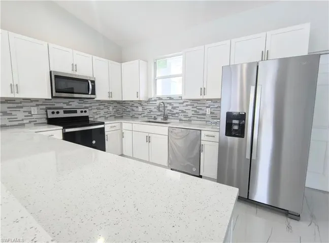 Kitchen featuring sink, appliances with stainless steel finishes, tasteful backsplash, and white cabinets