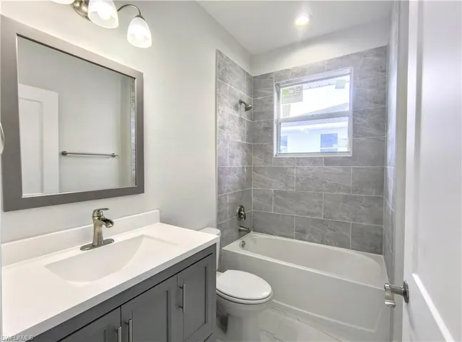 Full bathroom featuring vanity, toilet, tile patterned floors, and tiled shower / bath