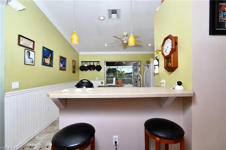 Kitchen featuring a breakfast bar area, a wainscoted wall, visible vents, a peninsula, and crown molding