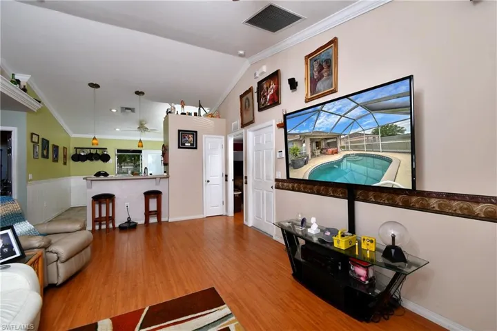 Living area with visible vents, wood finished floors, ceiling fan, and ornamental molding