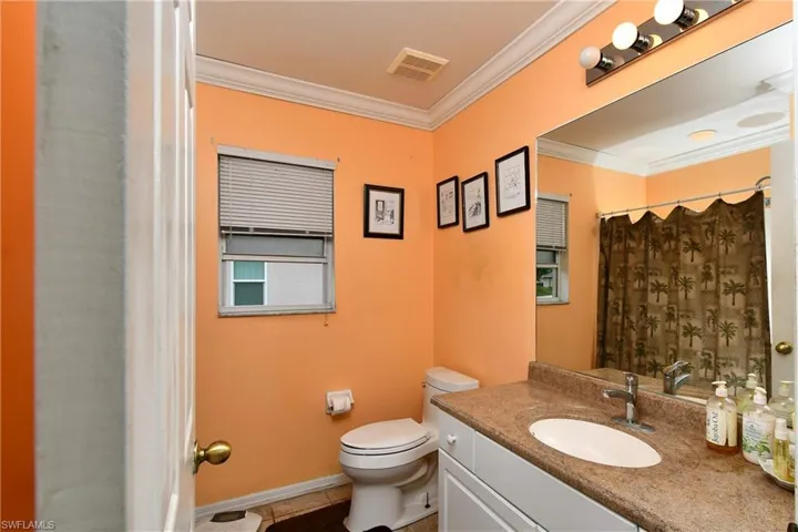 Full bath featuring vanity, baseboards, visible vents, crown molding, and toilet