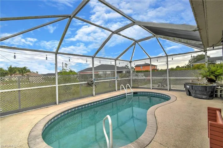 Pool featuring a patio area, glass enclosure, and fence