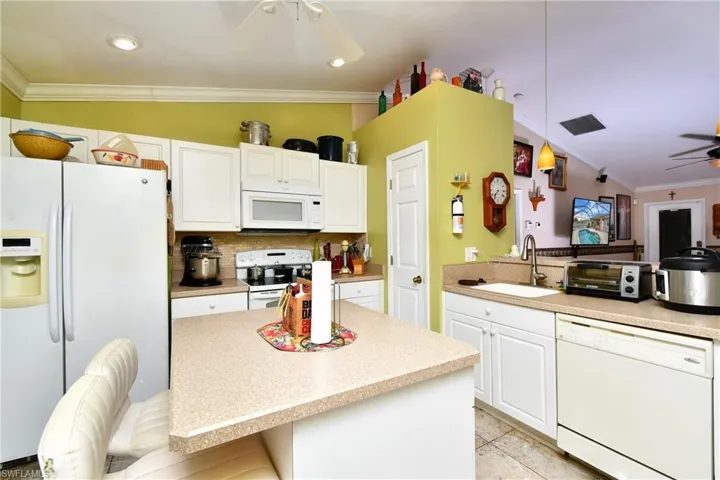 Kitchen featuring ceiling fan, ornamental molding, white cabinets, white appliances, and a sink