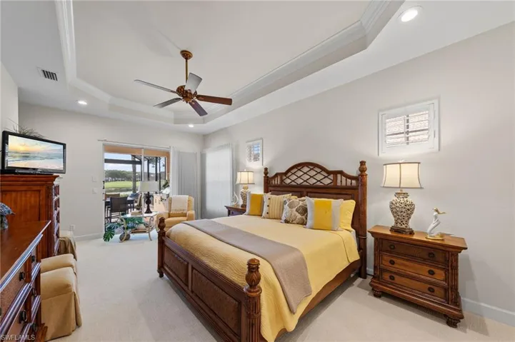 Tray ceiling with recessed lighting and a ceiling fan, plush carpet flooring, sliding glass door to an outdoor living space, and a shuttered window