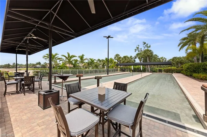 Outdoor bocce courts featuring two playing lanes, a paver patio, shaded seating areas, and surrounding palm trees