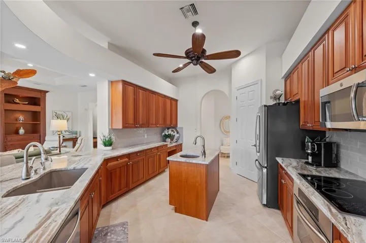Kitchen featuring wood cabinetry, light-toned countertops, an undermount sink, a central island, and stainless steel appliances