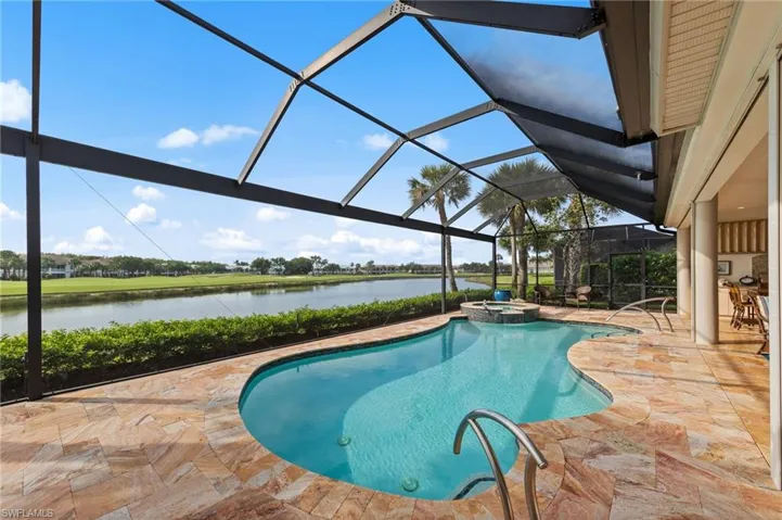 Screened lanai featuring a freeform pool with integrated spa and stone-finish decking
