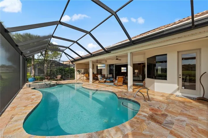 Screened pool enclosure with a freeform swimming pool and integrated spa