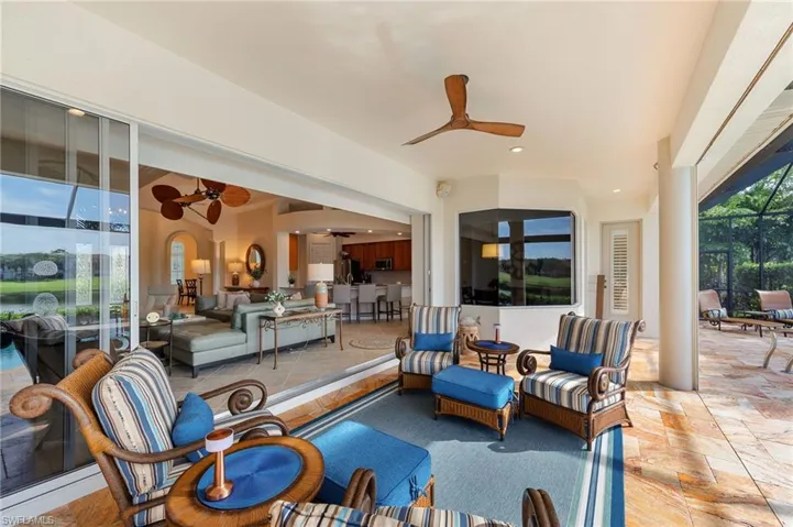 Covered lanai featuring large format tile flooring, a wood-finish ceiling fan, recessed lighting, and expansive sliding glass doors